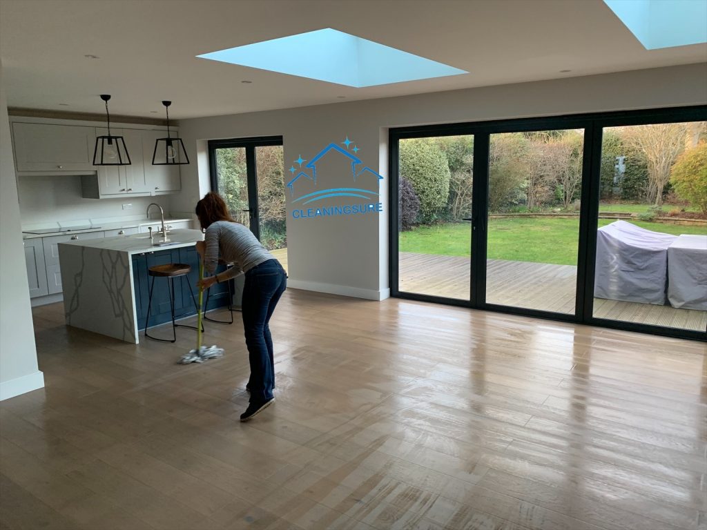 cleaner in london mopping a floor in a living room at the moving clean service