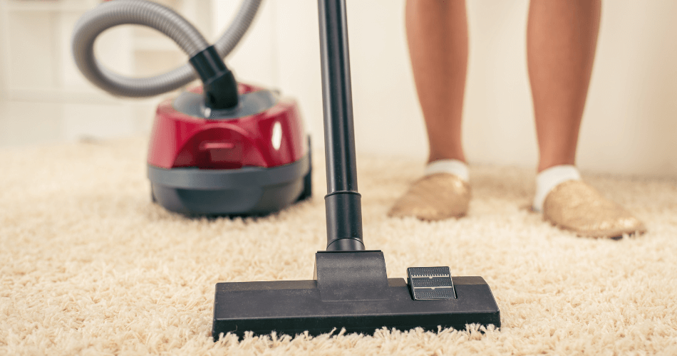 cleaner vacuuming a carpet in flat during an end of tenancy cleaning service in london