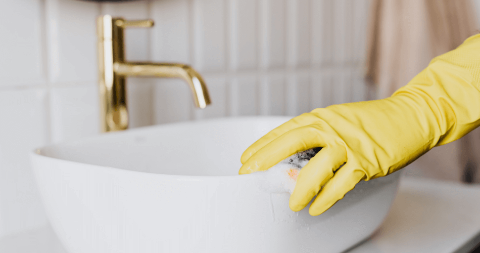 cleaner with yellow gloves polish a sing during an end of tenancy clean