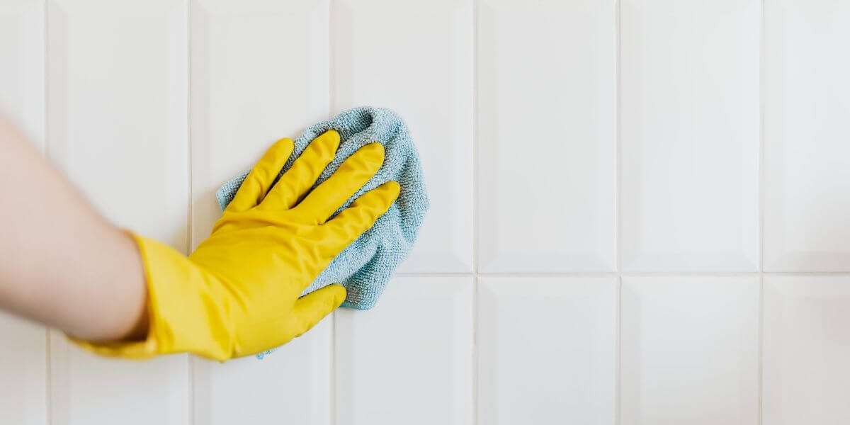 cleaners hand with yellow glove polish a tiles during end of tenancy cleaning service in london