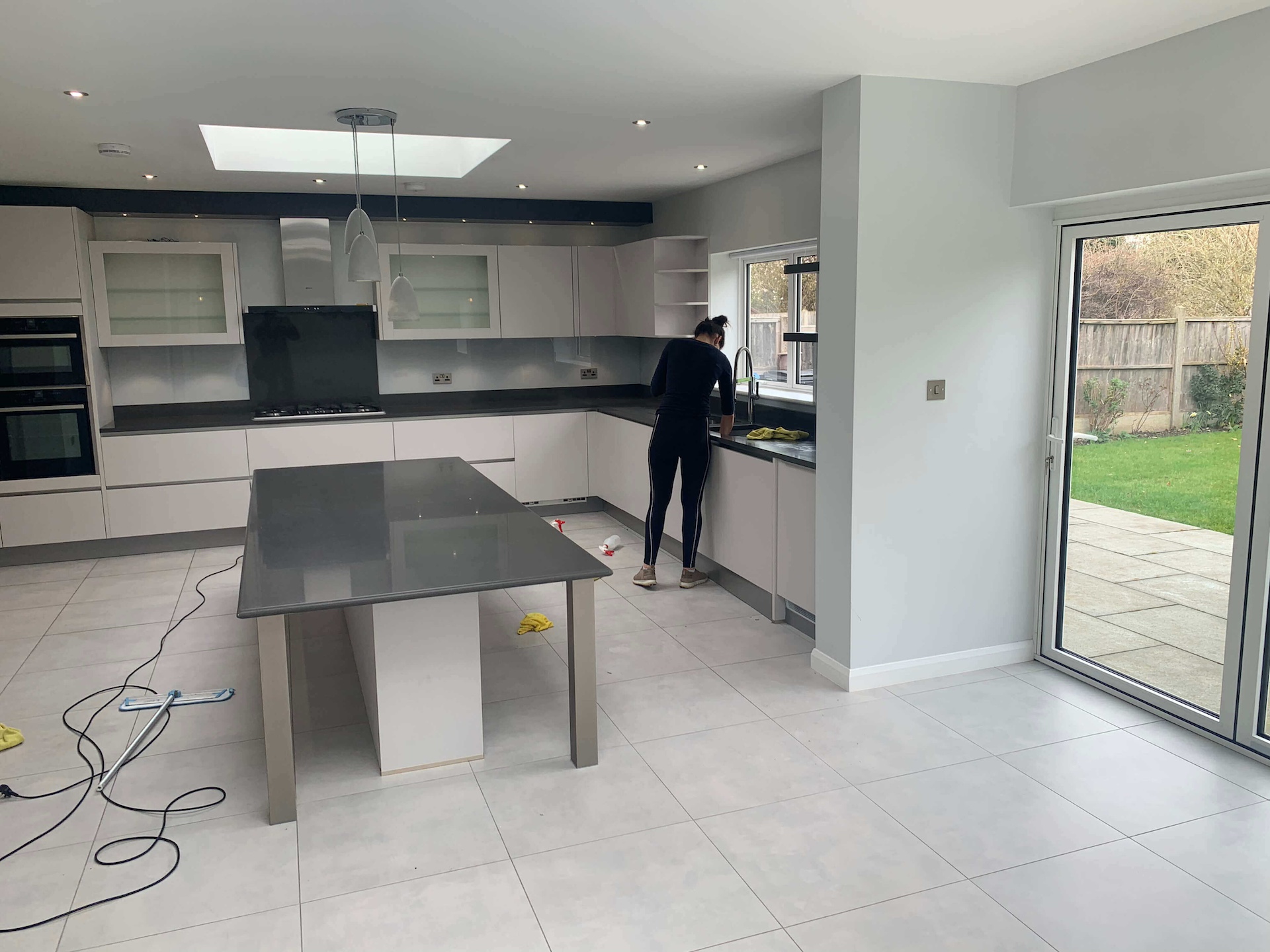 Professional female cleaner from Cleaningsure actively engaged in end of lease cleaning service in Ealing W5, wearing uniform and gloves, meticulously cleaning a living space to ensure top-notch cleanliness.
