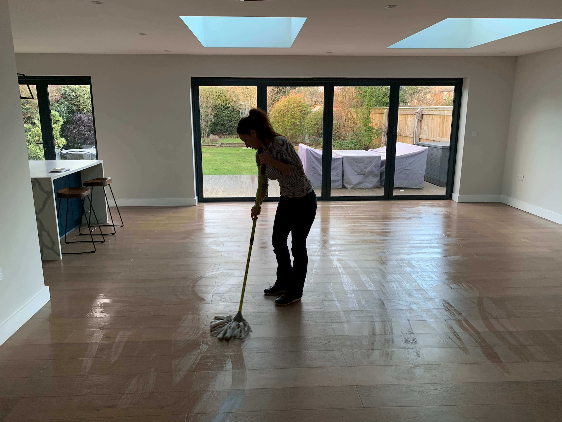 Skilled cleaner tidying up a living room in Battersea SW11 during a move-out cleaning service, demonstrating detailed cleaning techniques on furniture and flooring.